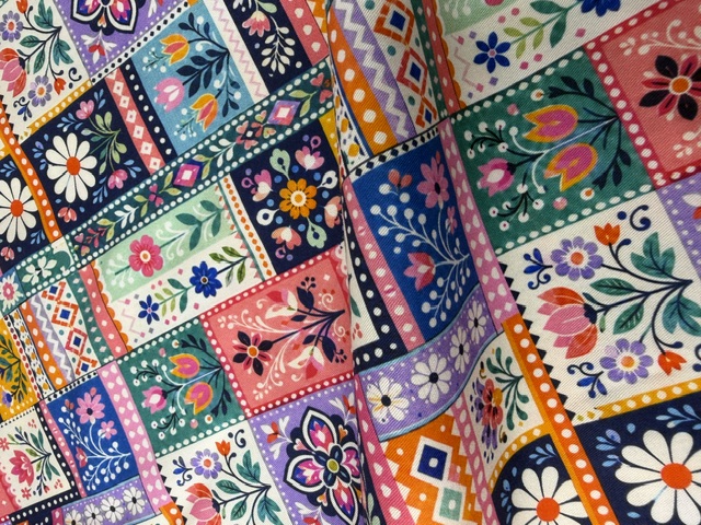 Draped Blush & Bloom cotton with a folk-art patchwork print β tulips, daisies and leafy vines in navy, coral, mint, marigold and lavender