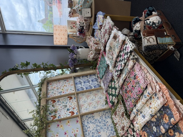 Handmade Bible/Journal covers and other fabric keepsakes arranged on a display table in the Blush & Bloom studio